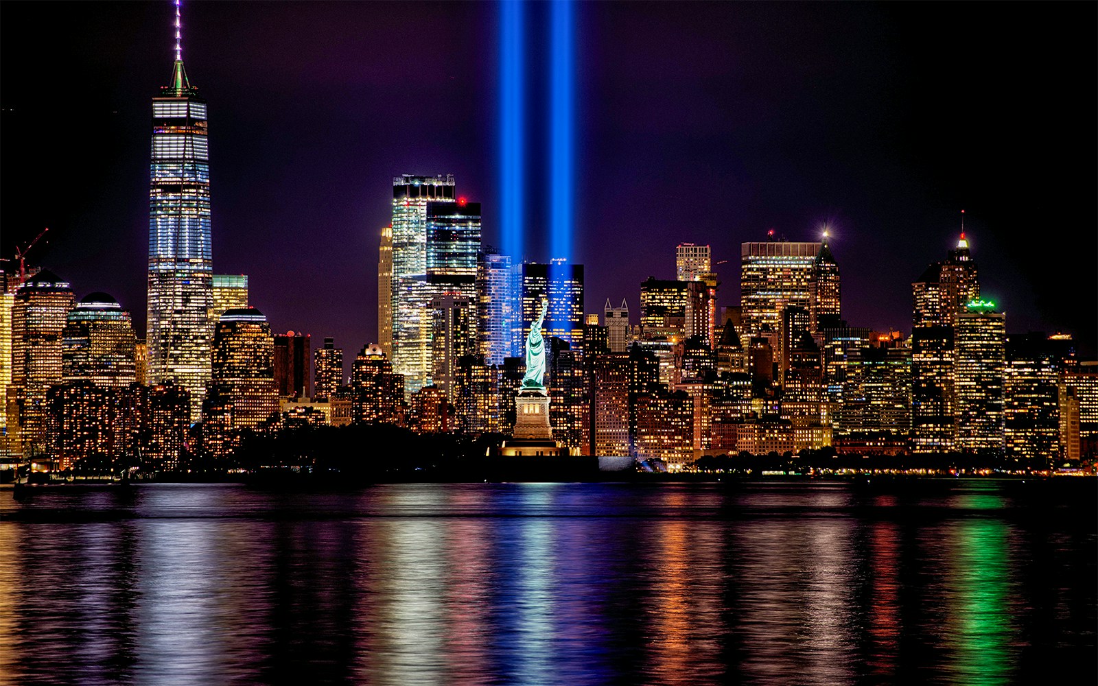 New York City skyline with iconic skyscrapers and the Statue of Liberty in the foreground.