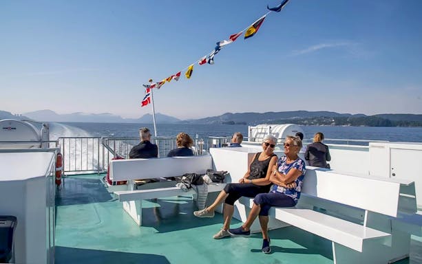 Guests on Mostraumen Fjord Cruise admiring scenic Norwegian fjord views.