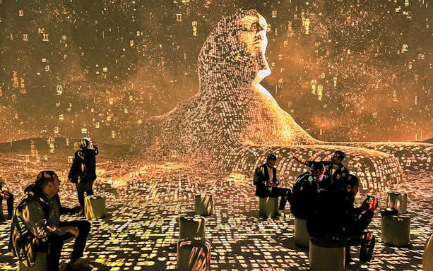Visitors seated around digital Sphinx projection with hieroglyphs.