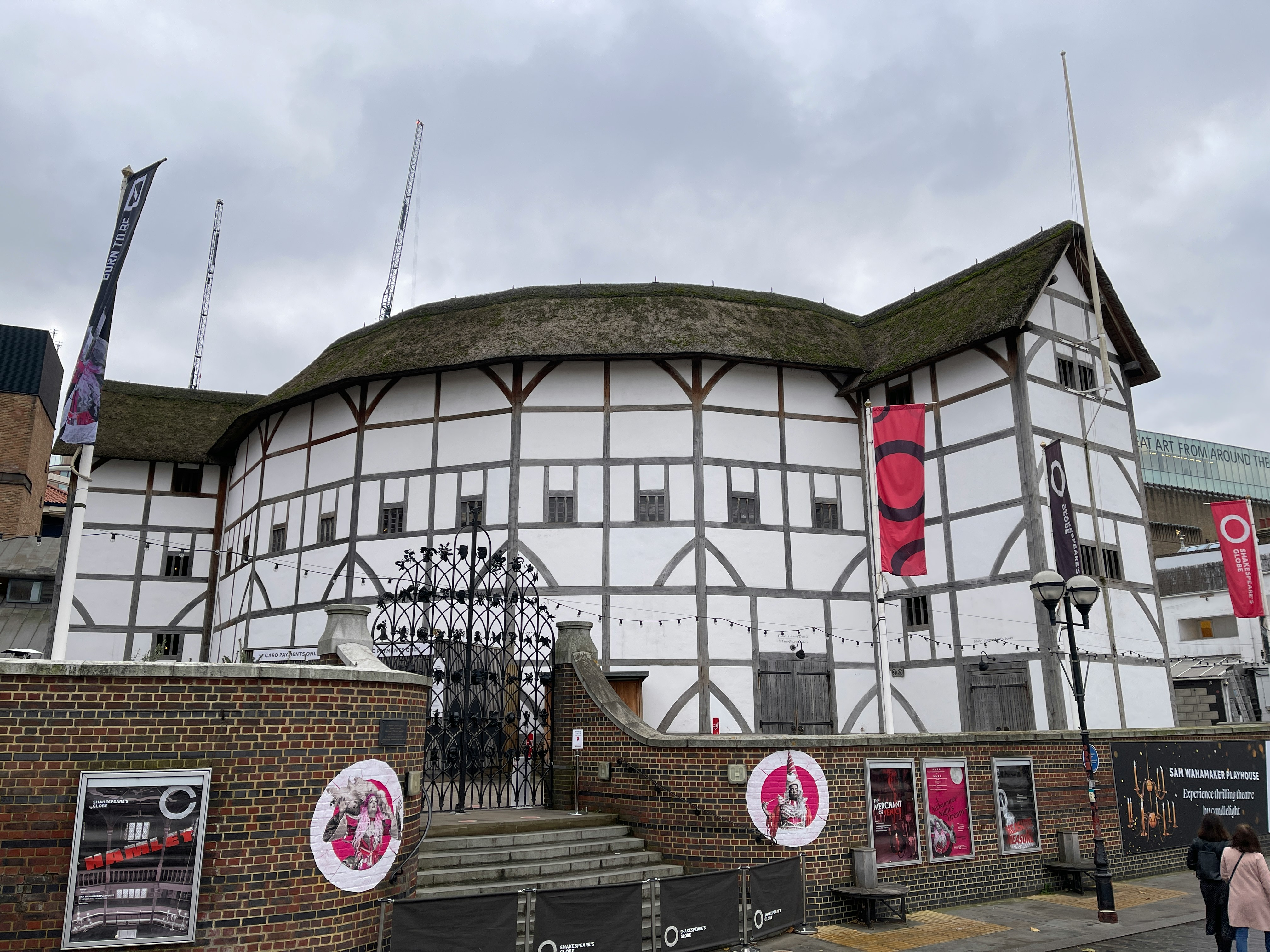 Shakespeare’s Globe entrance with banners and brick wall, London.