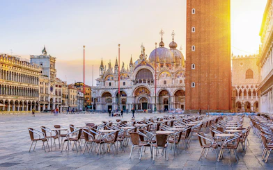 St. Mark's Basilica and Campanile in Venice with empty outdoor seating in foreground.