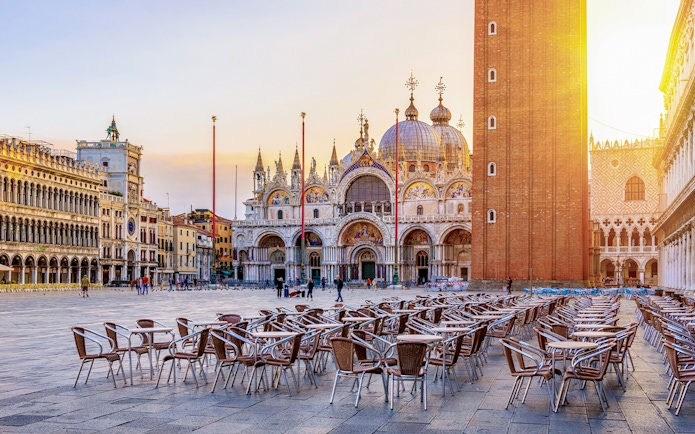 St. Mark's Basilica and Campanile in Venice with empty outdoor seating in foreground.