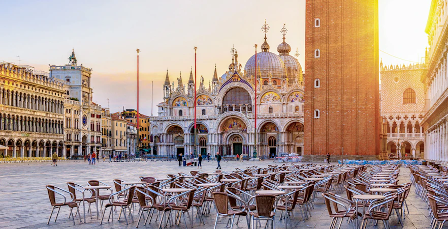 St. Mark's Basilica and Campanile in Venice with empty outdoor seating in foreground.
