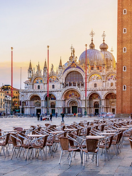 St. Mark's Basilica and Campanile in Venice with empty outdoor seating in foreground.