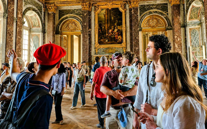 Visitors exploring the ornate interior of Versailles Palace during a guided tour.
