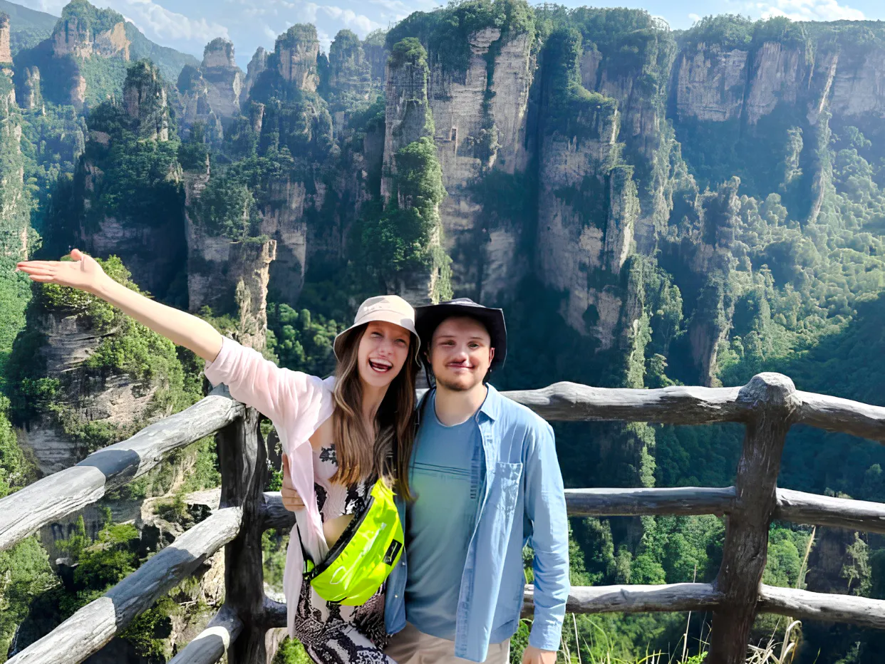 Visitors enjoying the view of Zhangjiajie's Avatar Mountains from a wooden railing.