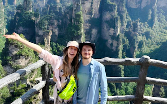 Visitors enjoying the view of Zhangjiajie's Avatar Mountains from a wooden railing.
