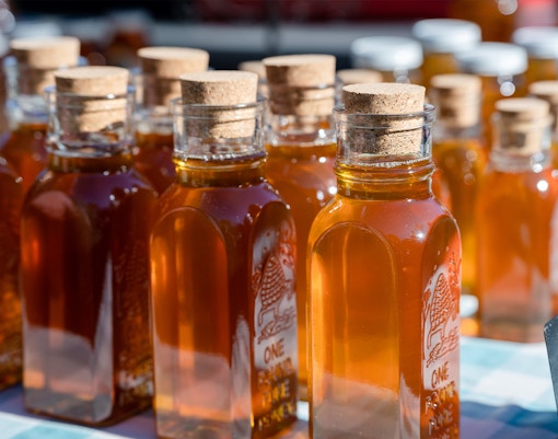 Bottles of honey with cork stoppers displayed at a local market.