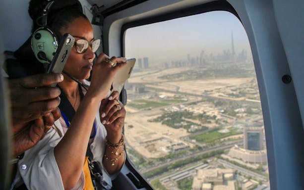 Visitors taking photos inside a helicopter over Dubai skyline.