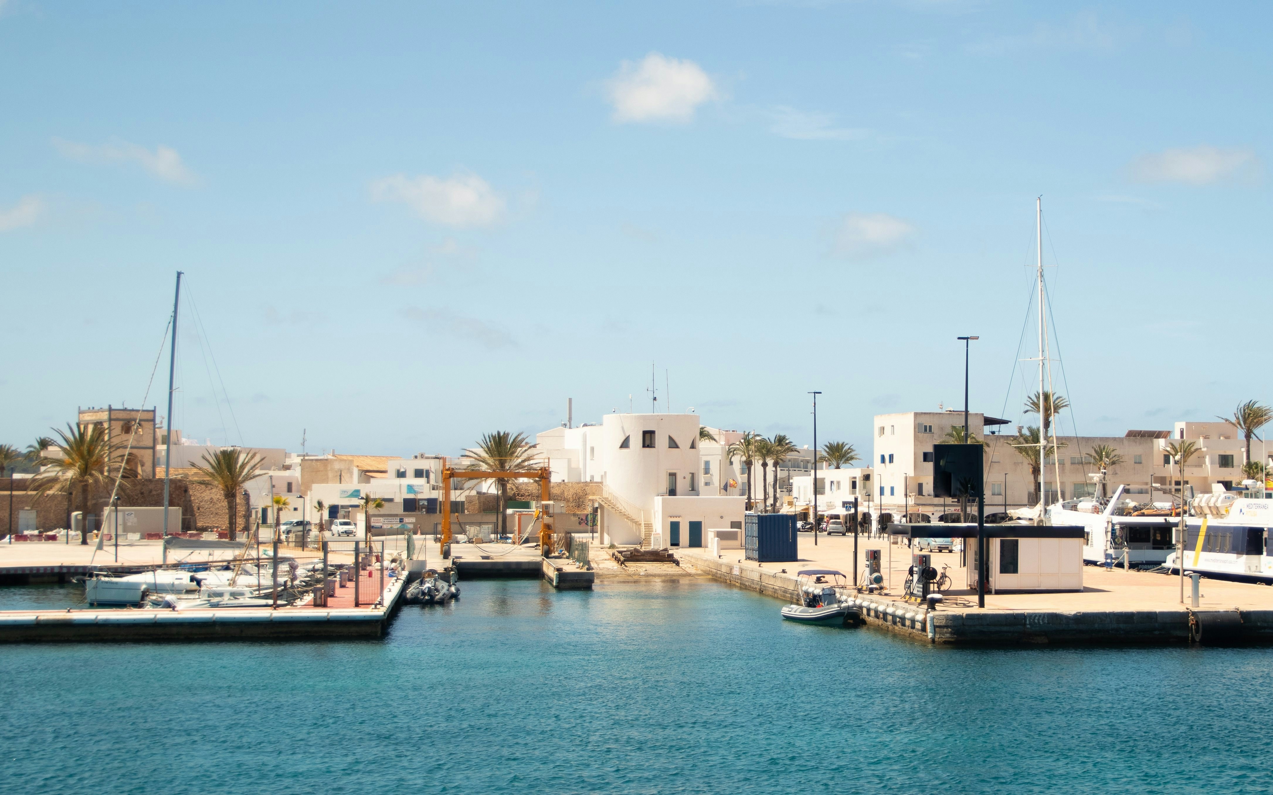 Formentera Port with boats docked and white buildings in the background.