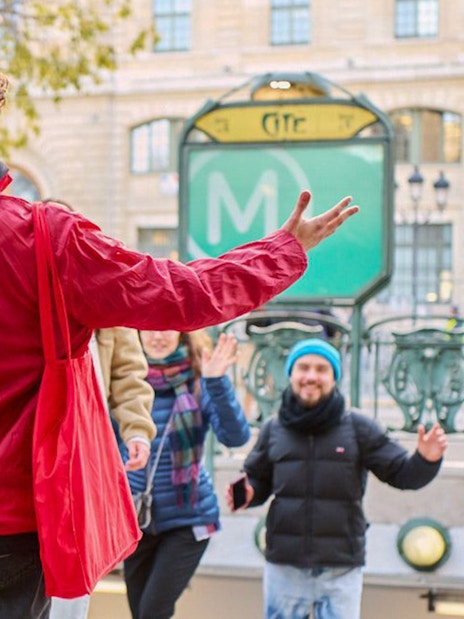 Tour guide leading a group near Notre Dame, Paris, with a metro entrance in the background.