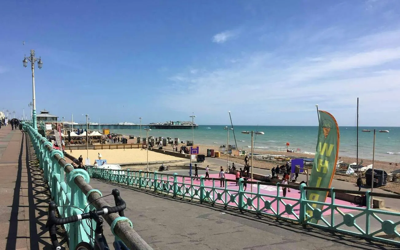 Brighton seafront view with promenade, beach, and pier in the background.