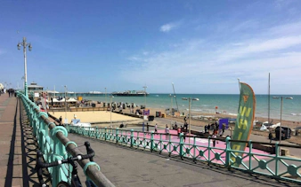Brighton seafront view with promenade, beach, and pier in the background.