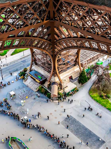 View from Eiffel Tower summit, Paris, showing people in line and nearby park.