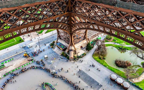 View from Eiffel Tower summit, Paris, showing people in line and nearby park.