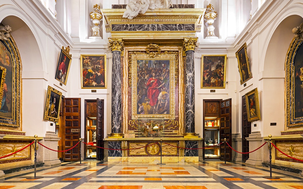Interior of the Cathedral of Toledo featuring ornate paintings and marble columns.
