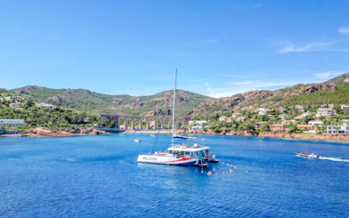 Catamaran in Villefranche bay with snorkelers in the water, surrounded by hills and coastal homes.