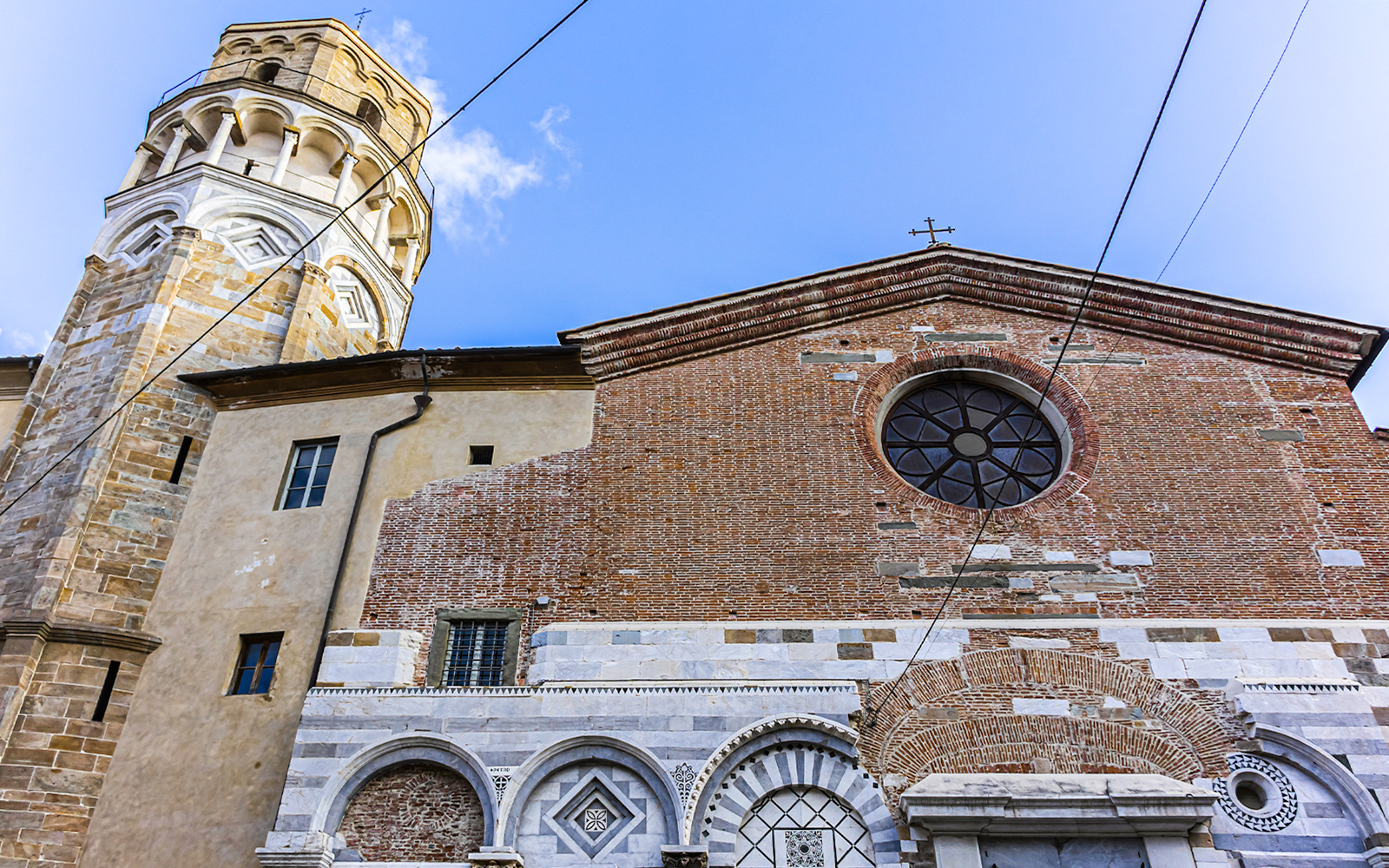 Tower and Church of San Nicola in Pisa with brick facade and circular window.