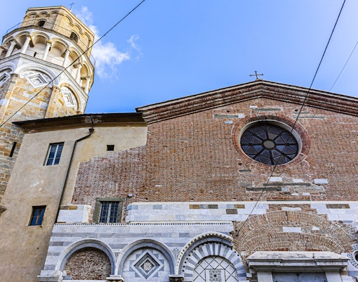Tower and Church of San Nicola in Pisa with brick facade and circular window.