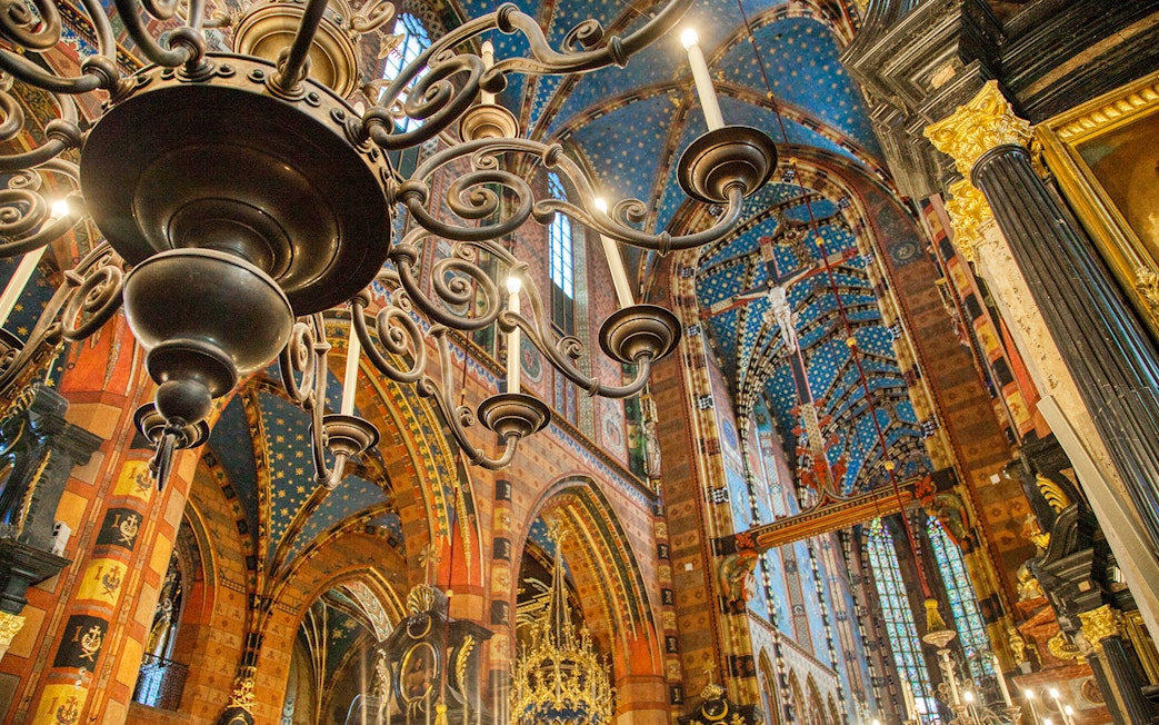Krakow church interior with ornate chandelier and colorful vaulted ceiling.