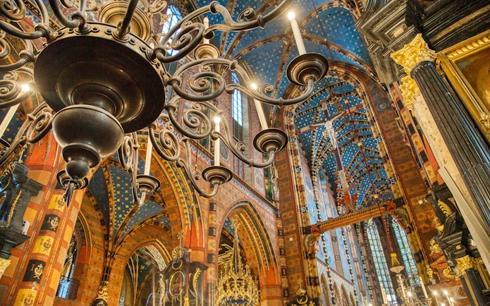 Krakow church interior with ornate chandelier and colorful vaulted ceiling.