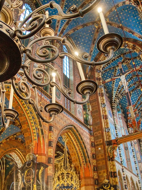 Krakow church interior with ornate chandelier and colorful vaulted ceiling.