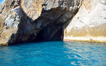 Gruta Azul entrance with rocky cliffs and blue water in Arraial do Cabo, Brazil.