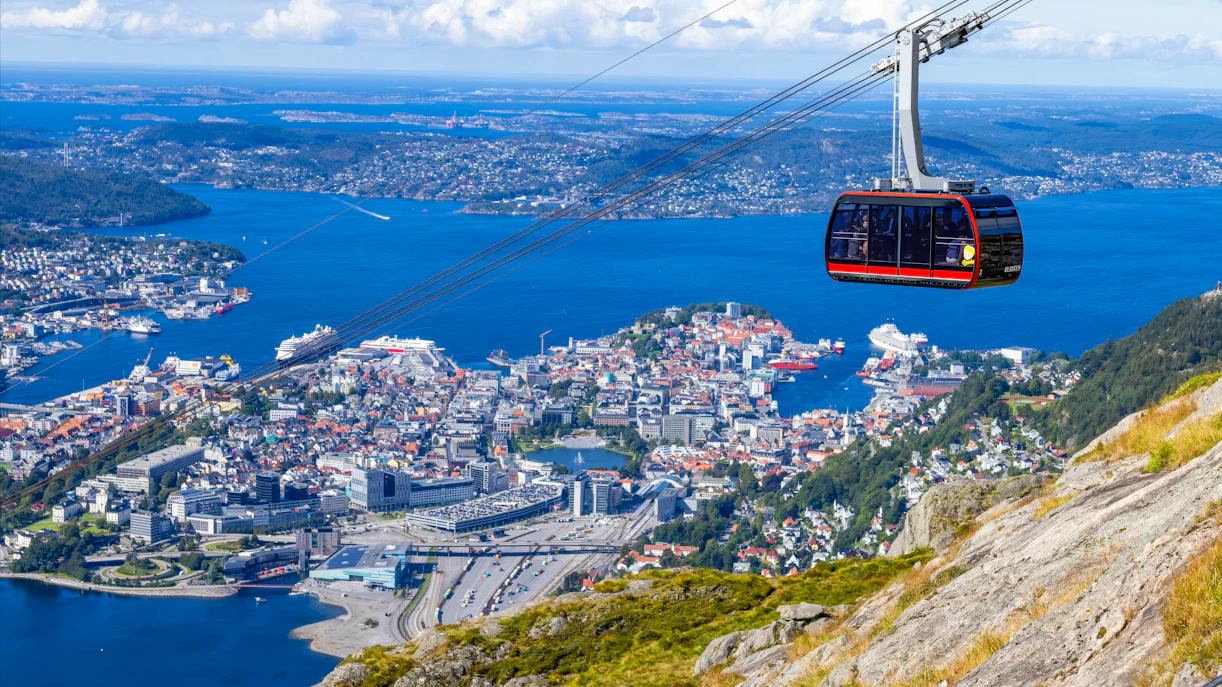 Ulriken cable car ascending over Bergen, Norway with city and fjord views.