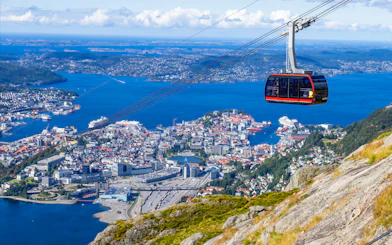 Ulriken cable car ascending over Bergen, Norway with city and fjord views.