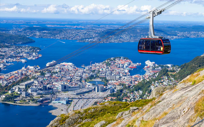 Ulriken cable car ascending over Bergen, Norway with city and fjord views.