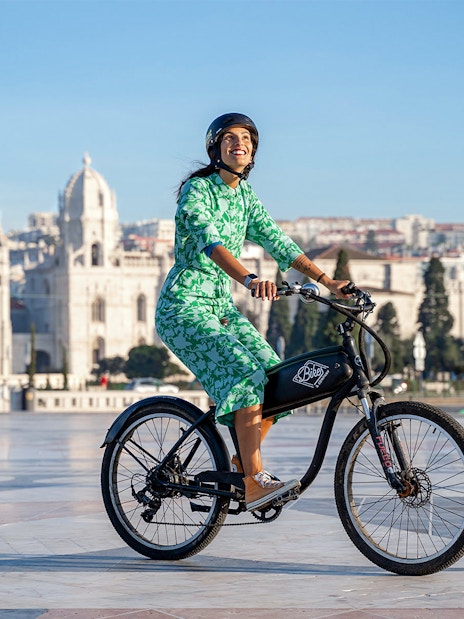 Person riding an electric bike in front of Jerónimos Monastery, Lisbon.