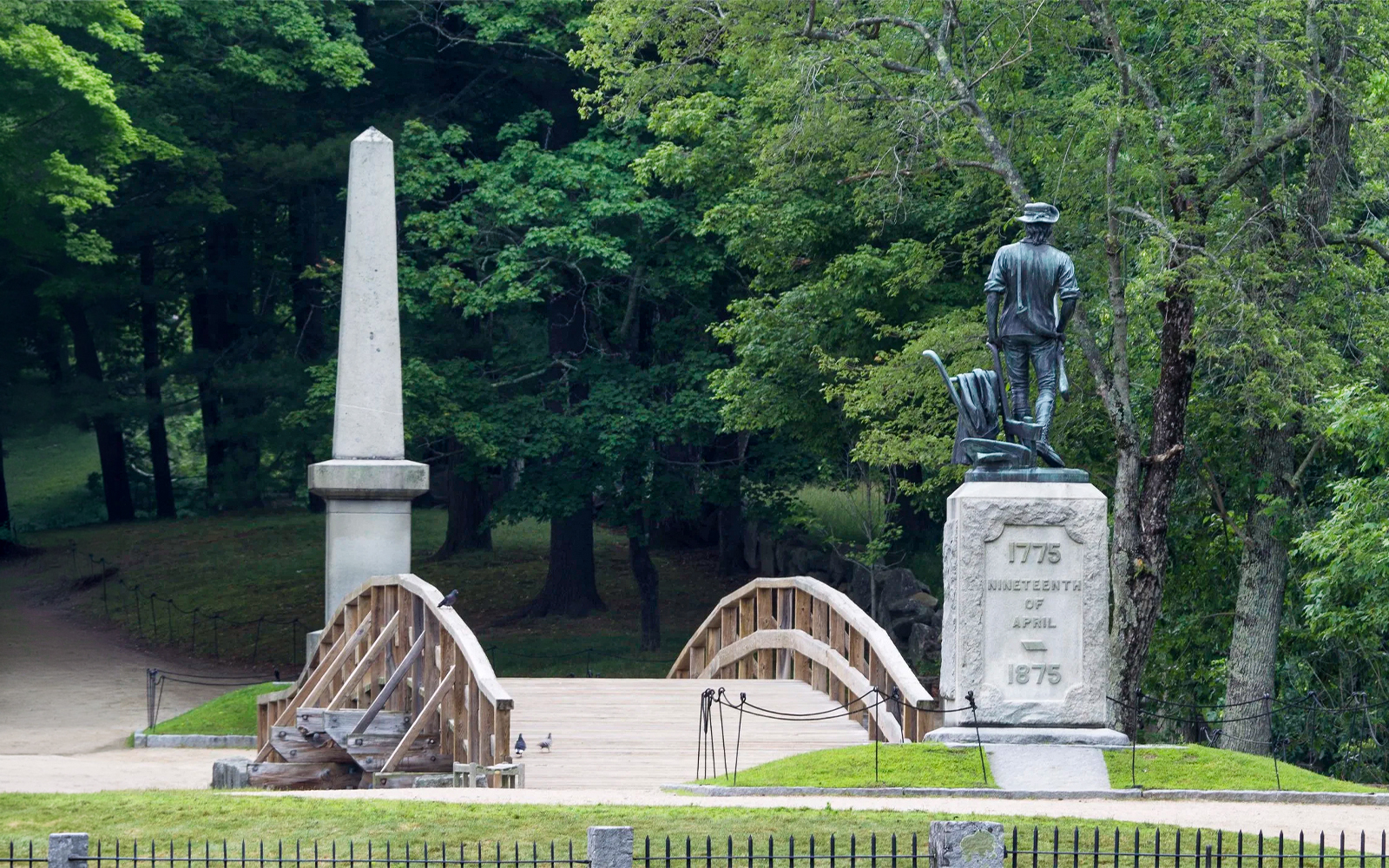 North Bridge and Minuteman Statue in Boston surrounded by trees.