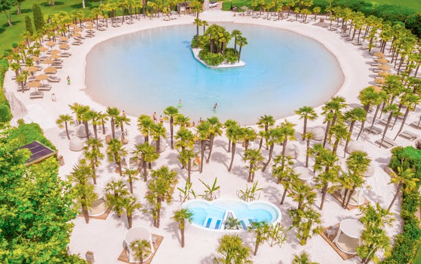 Aerial view of Parco Cavour Water Park with palm trees and lagoon.