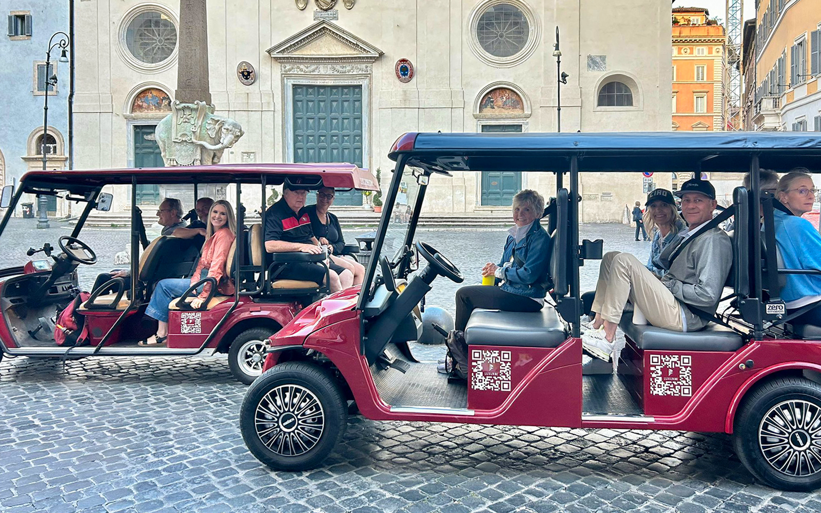 Golf carts with tourists in front of a historic building in Rome.
