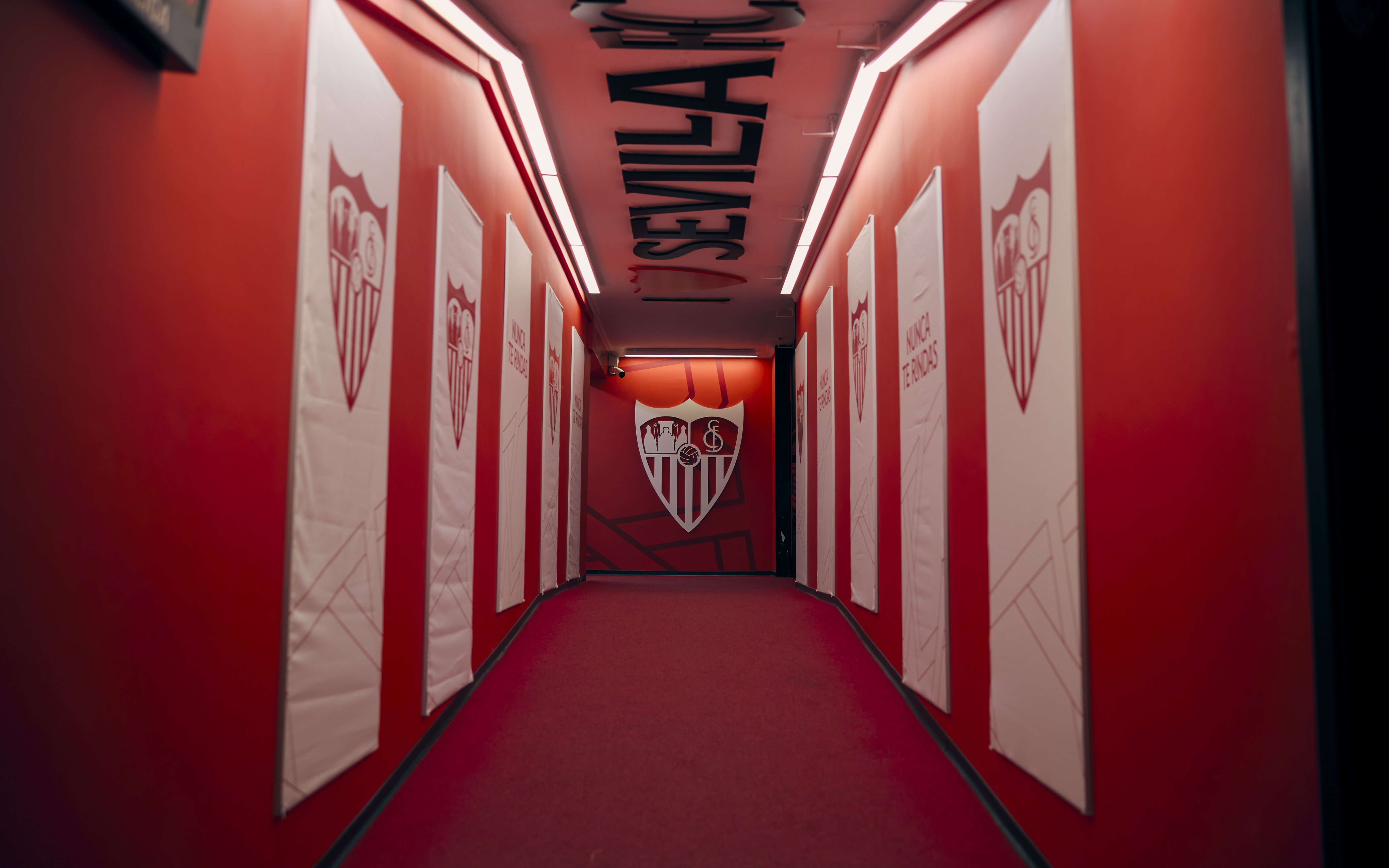 Players' tunnel at Ramón Sánchez-Pizjuán Stadium with Sevilla FC logos on red walls.