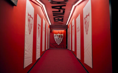 Players' tunnel at Ramón Sánchez-Pizjuán Stadium with Sevilla FC logos on red walls.