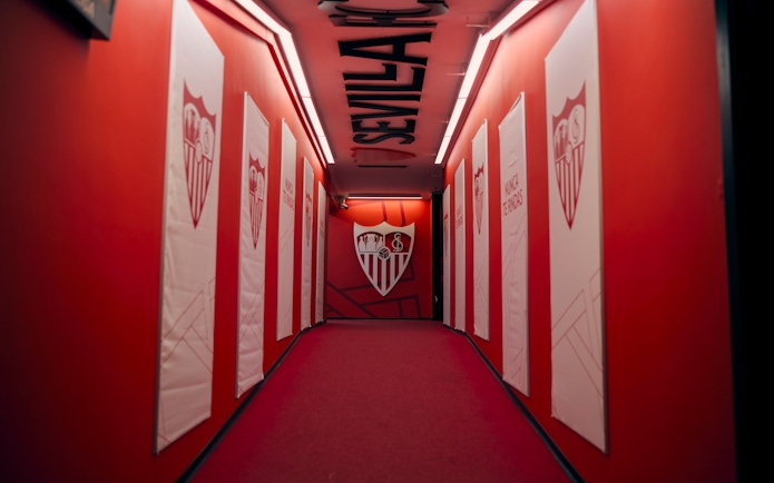 Players' tunnel at Ramón Sánchez-Pizjuán Stadium with Sevilla FC logos on red walls.