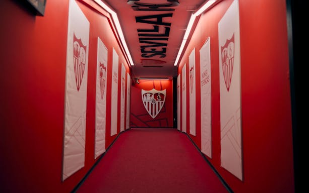 Players' tunnel at Ramón Sánchez-Pizjuán Stadium with Sevilla FC logos on red walls.