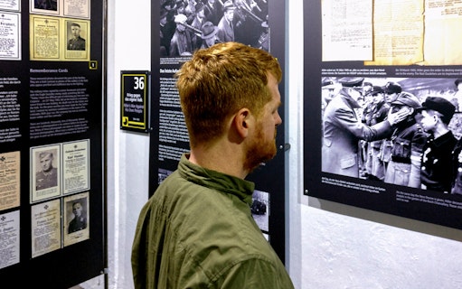 Visitor examining historical exhibits at Berlin Story Bunker.