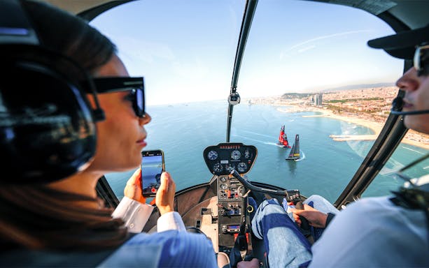 Helicopter view of America's Cup sailboats near Barcelona coast.
