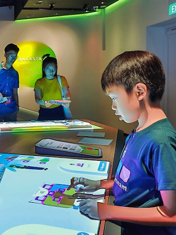 Child interacting with digital exhibit at Petrosains Discovery Centre.