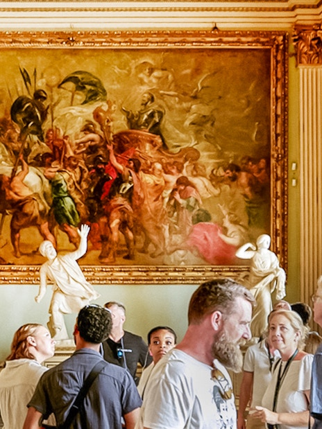 Visitors observing paintings and sculptures in the Rubens Niobe Room at Uffizi Gallery, Florence.