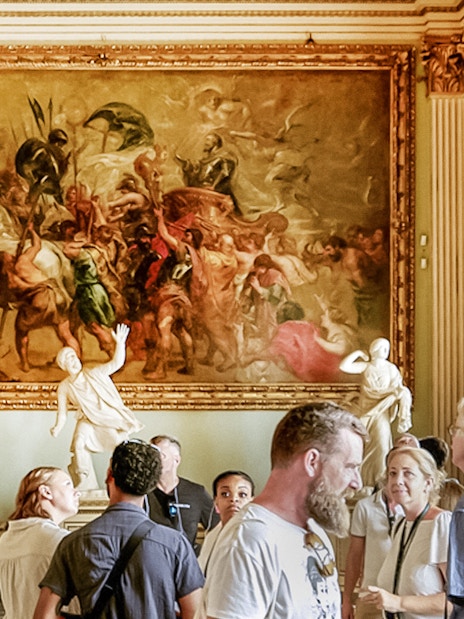 Visitors observing paintings and sculptures in the Rubens Niobe Room at Uffizi Gallery, Florence.