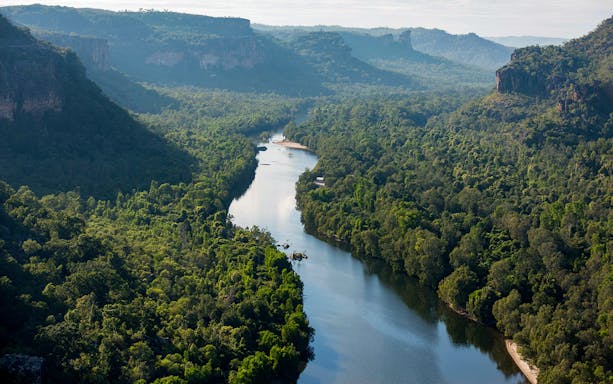 Aerial view of lush green landscape and winding river in Kakadu National Park, Australia.