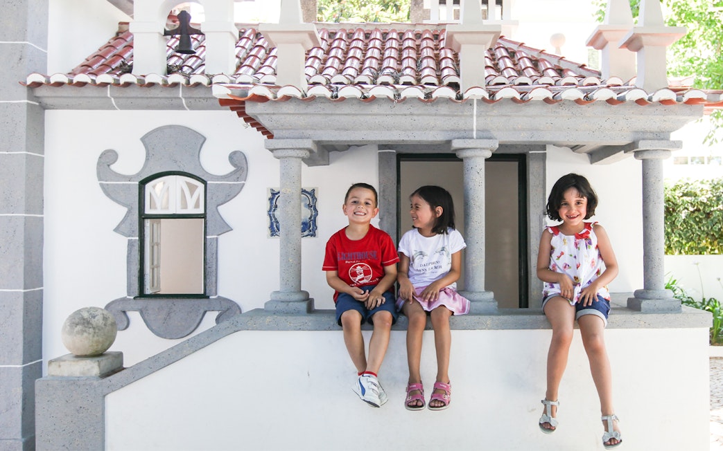 Children sitting on a miniature building at Portugal dos Pequenitos, Coimbra.