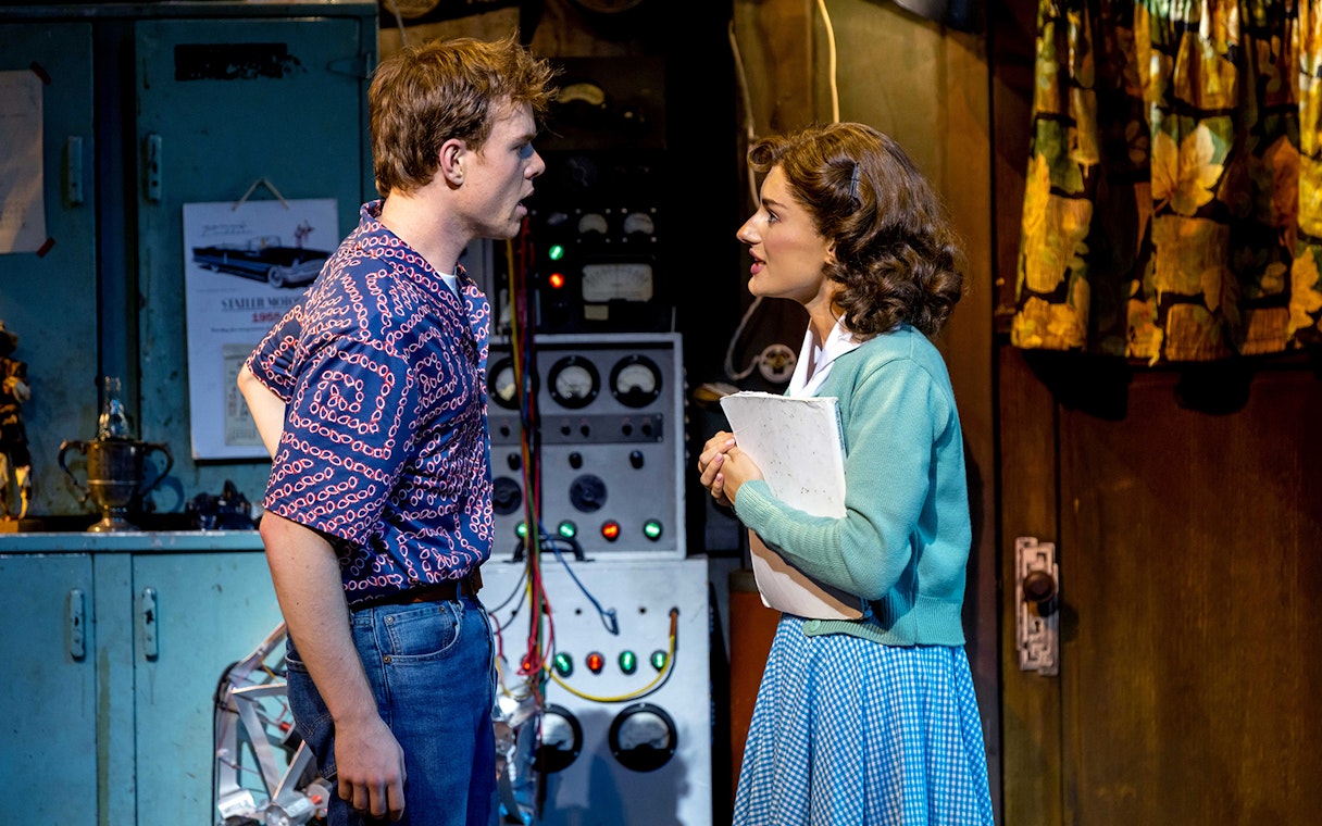 Two actors in a "Back to the Future" stage scene with vintage equipment.