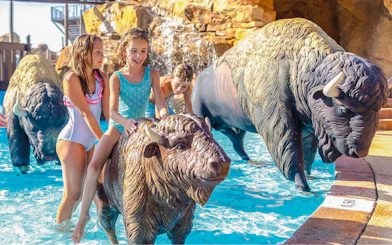 Kids riding animal sculptures in Western Water Park pool.