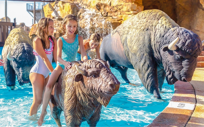 Kids riding animal sculptures in Western Water Park pool.