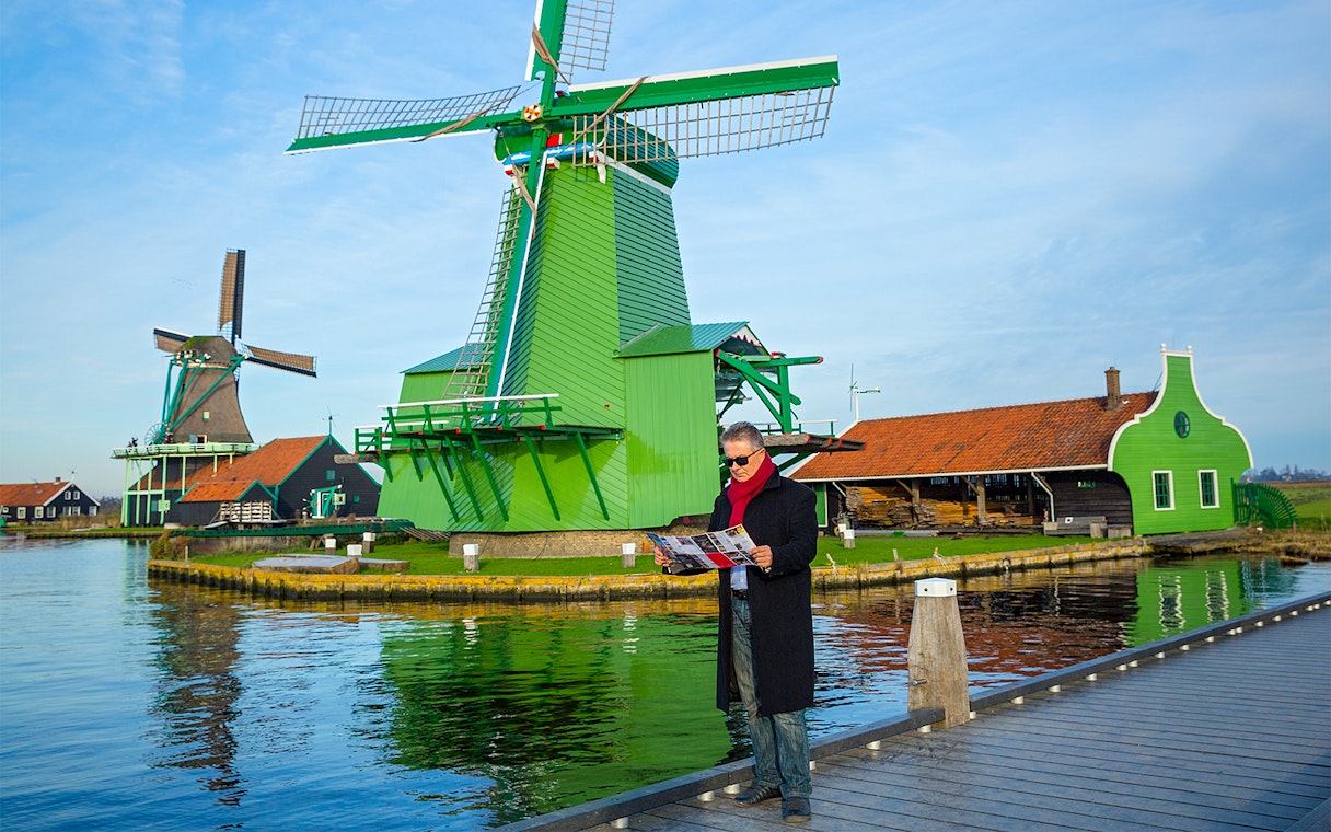 Man with a map near windmills in Zaanse Schans, Netherlands.