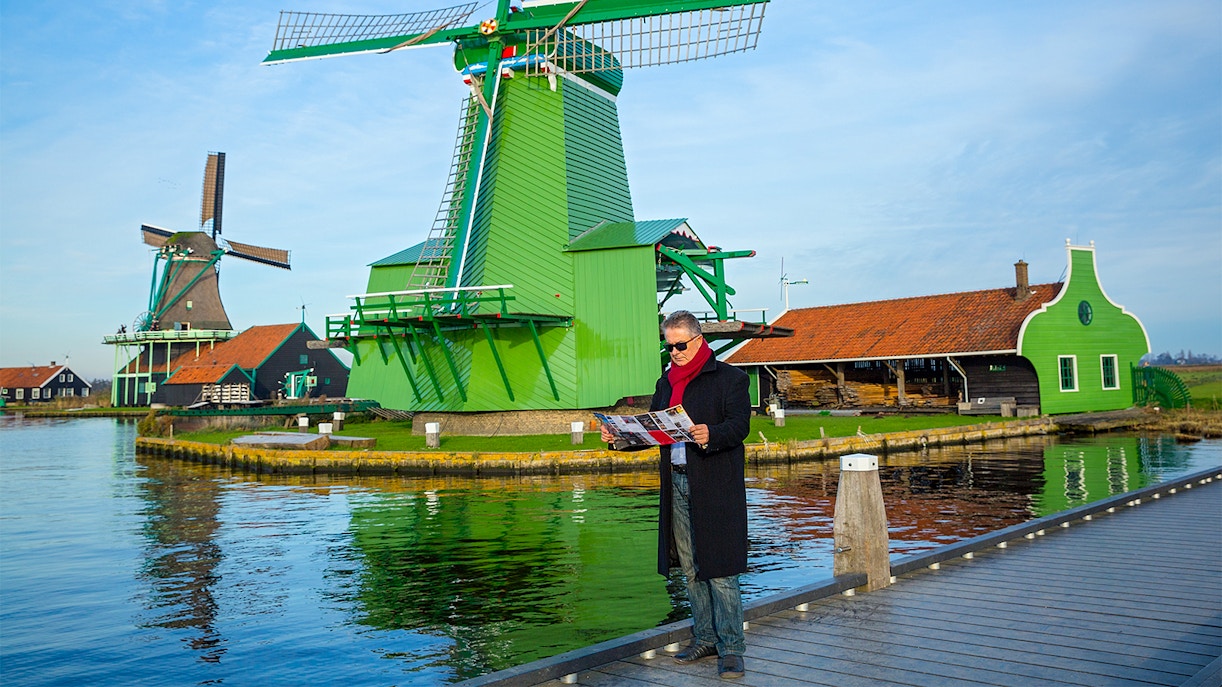 Man with a map near windmills in Zaanse Schans, Netherlands.